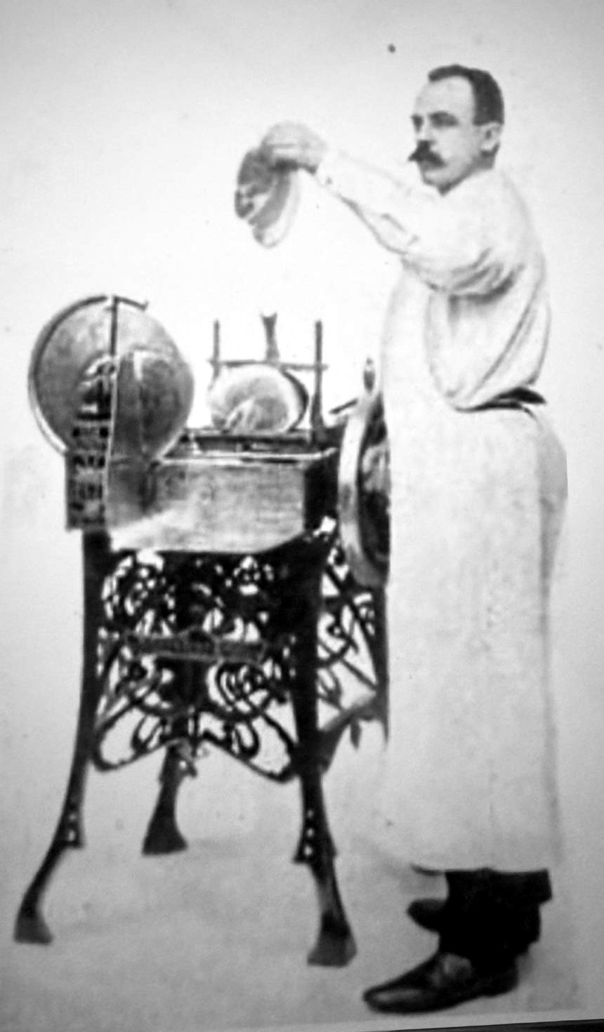 Photo historique de Wilhelmus van Berkel en blouse blanche de boucher, à côté de sa première trancheuse sur un pied en fonte ouvragé